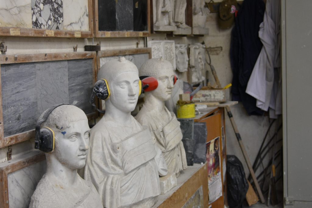 Busti romani con cuffie alle orecchie per parare il rumore.