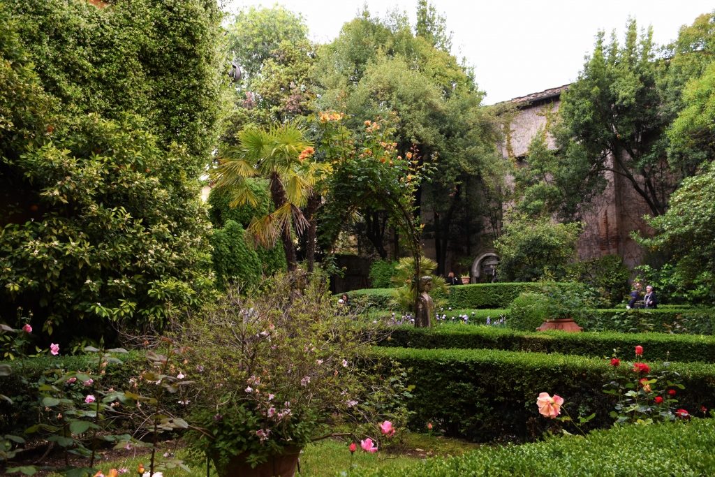 Giardino con fiori, siepi e alberi di diverso tipo.