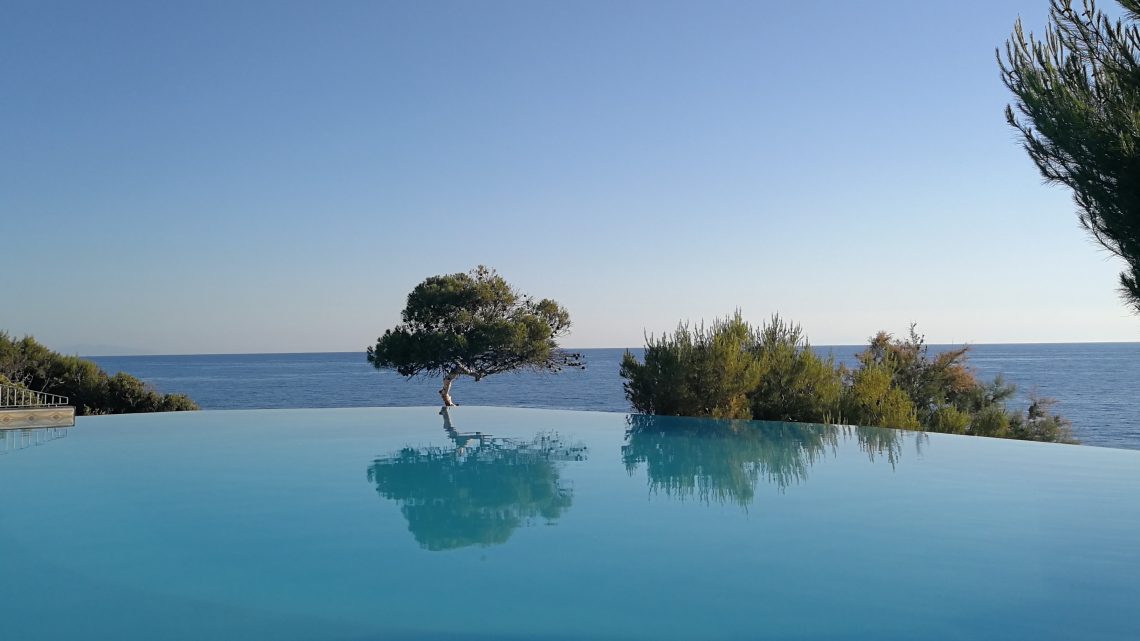 Piscina con pino e sfondo il mare.