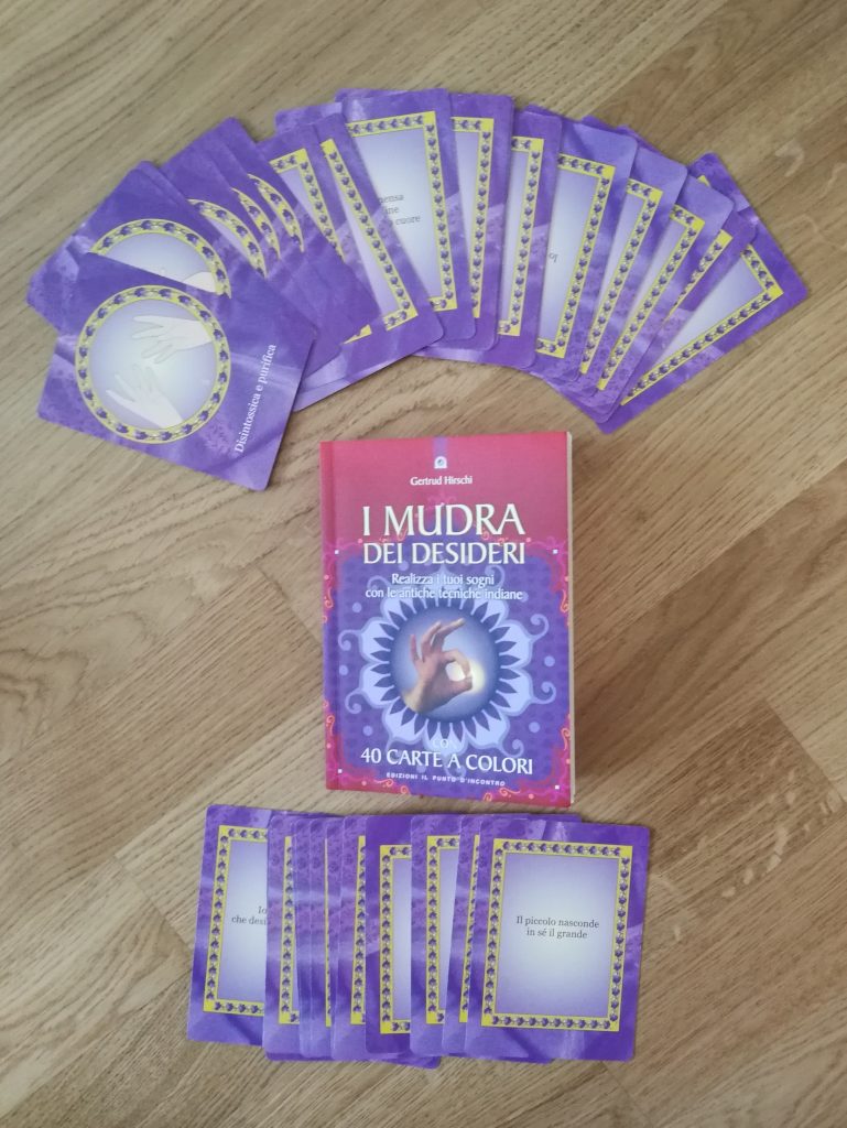 Libro dedicato ai mudra e le relative carte sparse sul parquet.