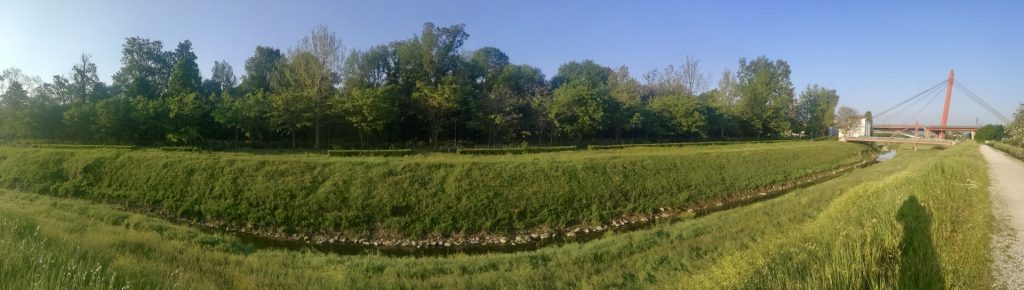 Parco verde e torrente, in lontananza il Ponte all'Indiano, un viadotto purpureo.