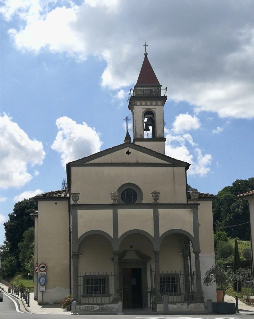 Chiesa con intonaco bianco e porticato, colonne in pietra grigia, campanile.