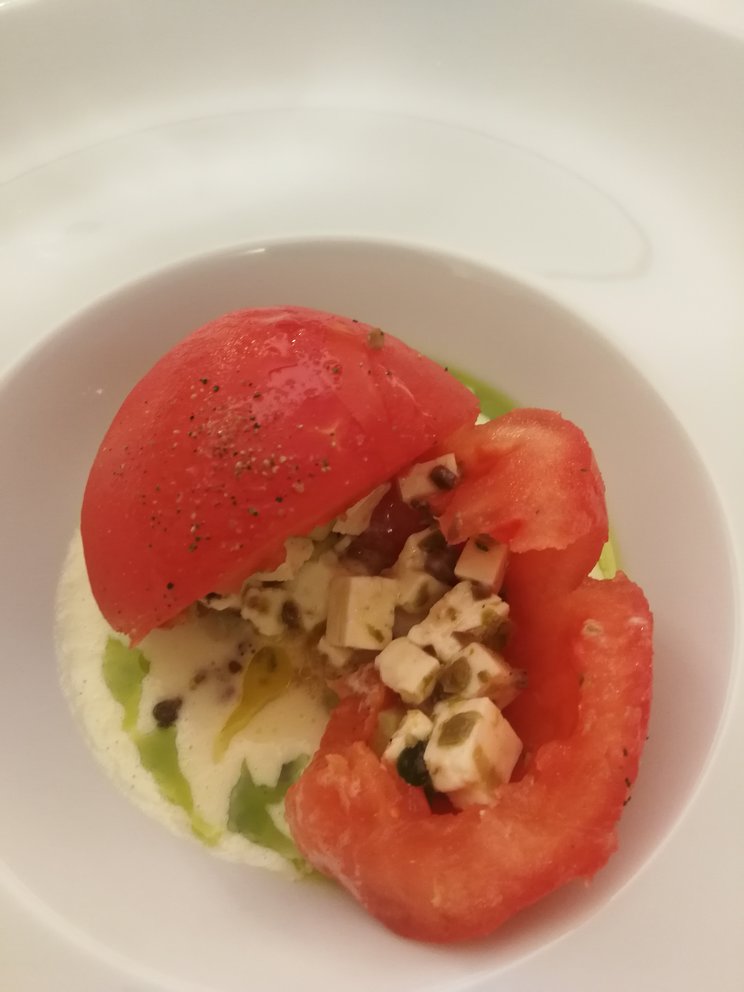 Piatto con pomodoro aperto e dentro formaggio a cubetti.
