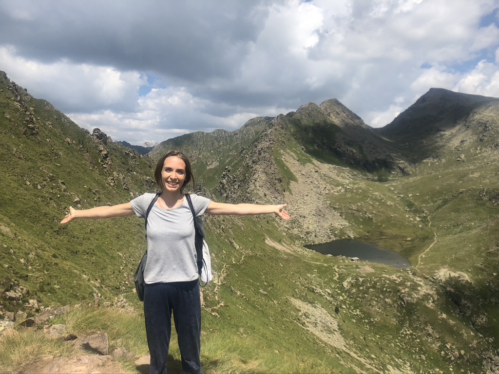 Federica sulla Cima Lusia, dietro i laghi di Lusia e panorama sulle catene montuose; verde dei prati e rocce.