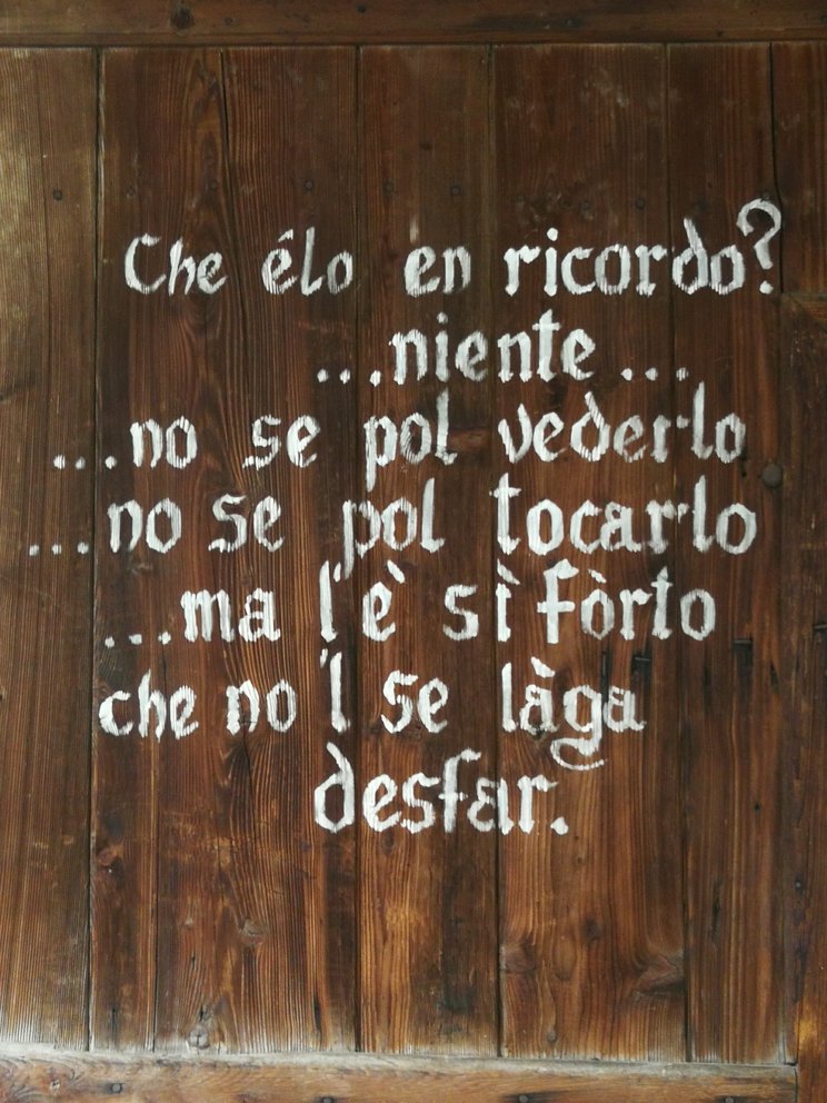 Scritta bianca su legno scuro, tutto in dialetto.