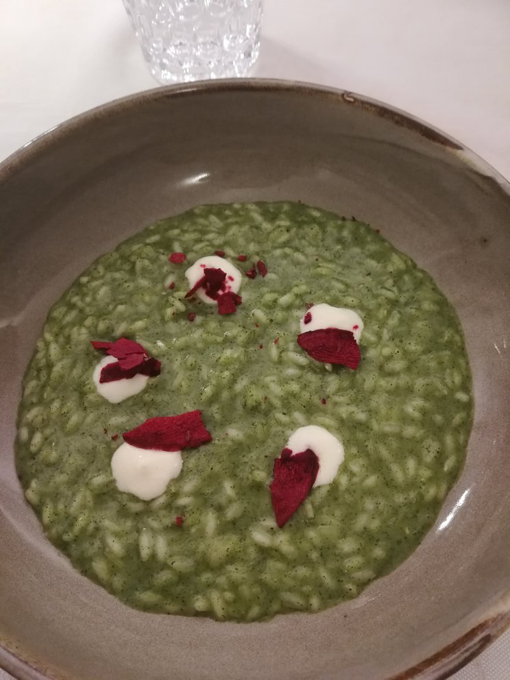 Risotto verde con pezzi di formaggio e barbabietola.