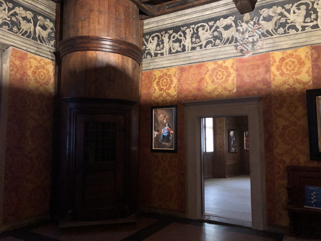 Stanza con affreschi e struttura in legno che contiene le scale.