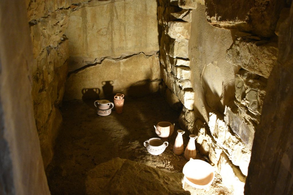 Interno con pietre e vasi di ceramica; luce artificale.