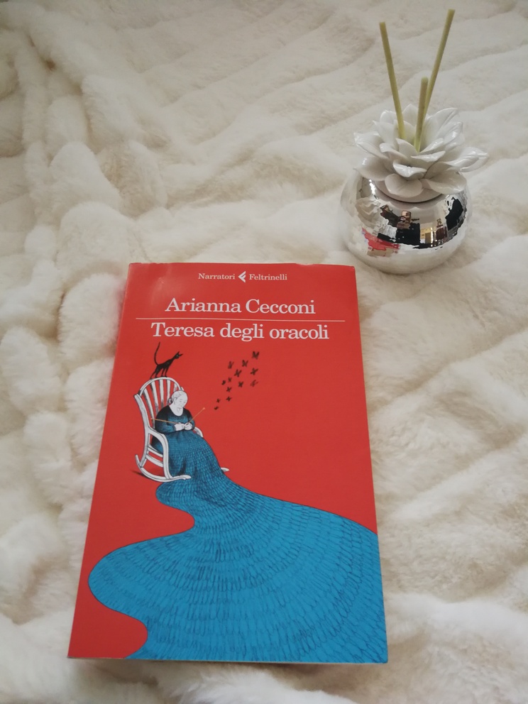 Copertina del libro su coperta bianca e profumatore per ambienti a forma di rosa bianca.