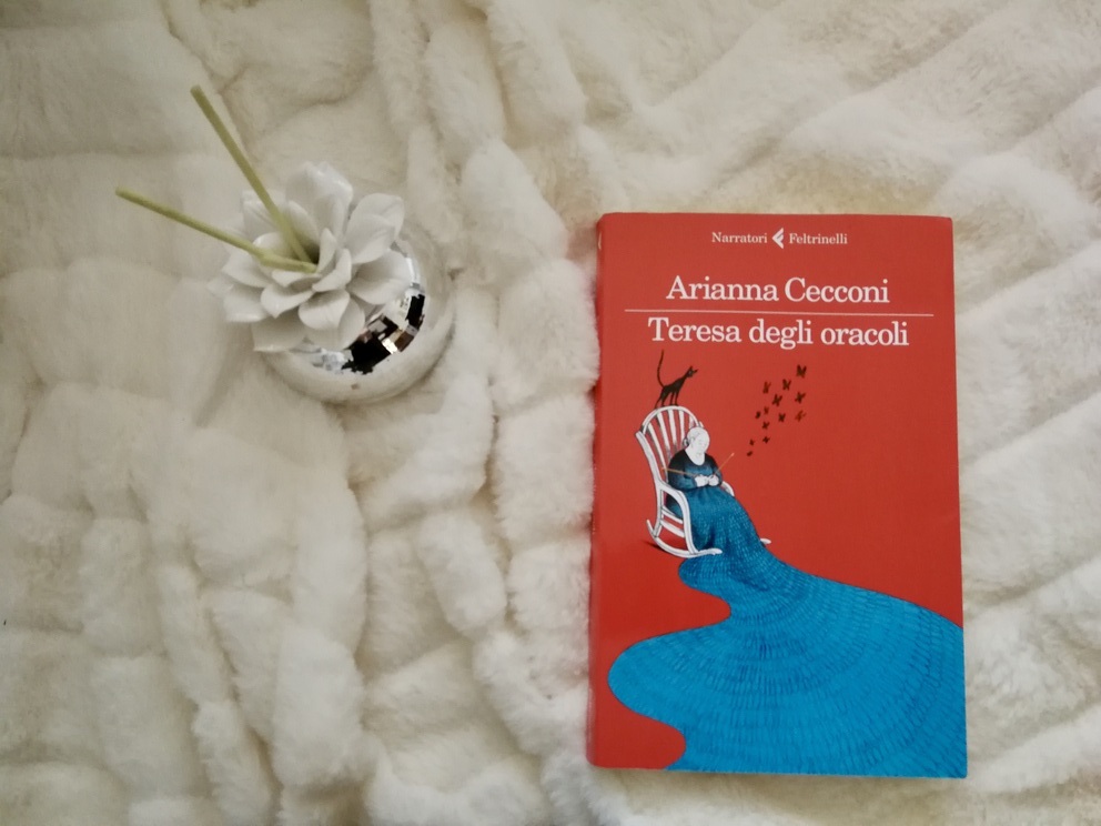 Copertina del libro su coperta bianca e profumatore per ambienti a forma di rosa bianca.