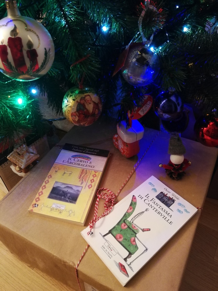 Libri Il cervo e l'arcobaleno e Il fantasma di Canterville sopra un pacco e sotto l'albero di natale.