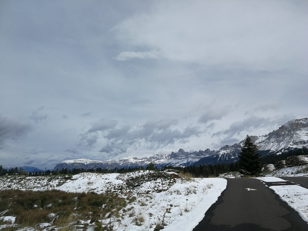 Paesaggio innevato: luna strada scura in un prato con neve, montagne sullo sfondo.