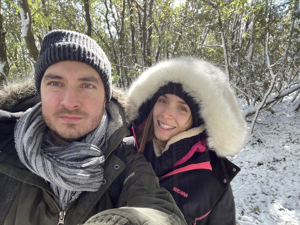 Lorenzo e Federica sorridenti nel bosco innevato.