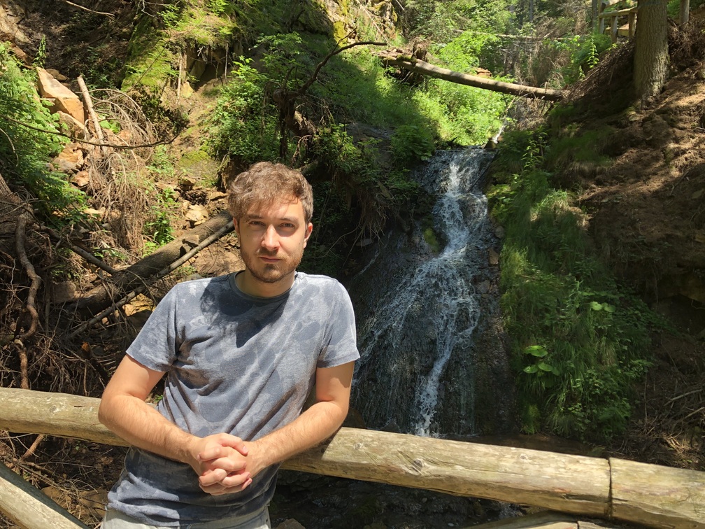 Percorso delle cascatelle - Lorenzo appoggiato alla staccionata in legno, ponte in legno, alberi e cascata.