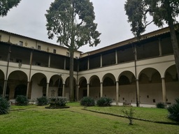 Chiostro della Chiesa del Carmine: verde prato, alberi e due ordini di loggiati.