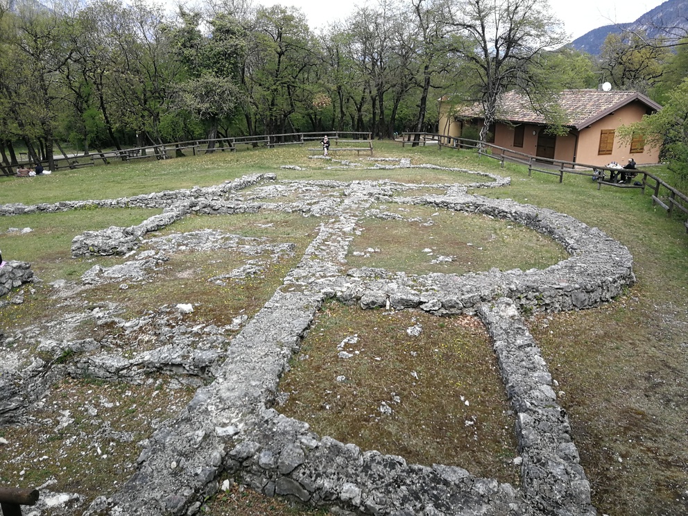 Resti in pietra di basilica, dietro casa e alberi.
