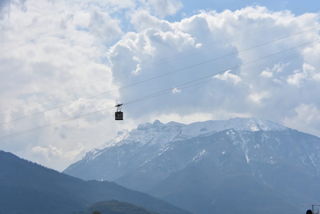 Funicolare tra le nuvole e dietro montagna innevata.