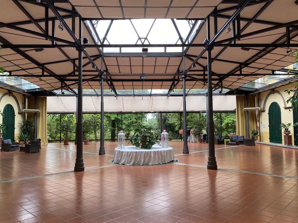 Villa Castelletti - Giardino d'inverno con soffitto bianco retto da pali neri, tavolo al centro e grandi spazi vuoti.