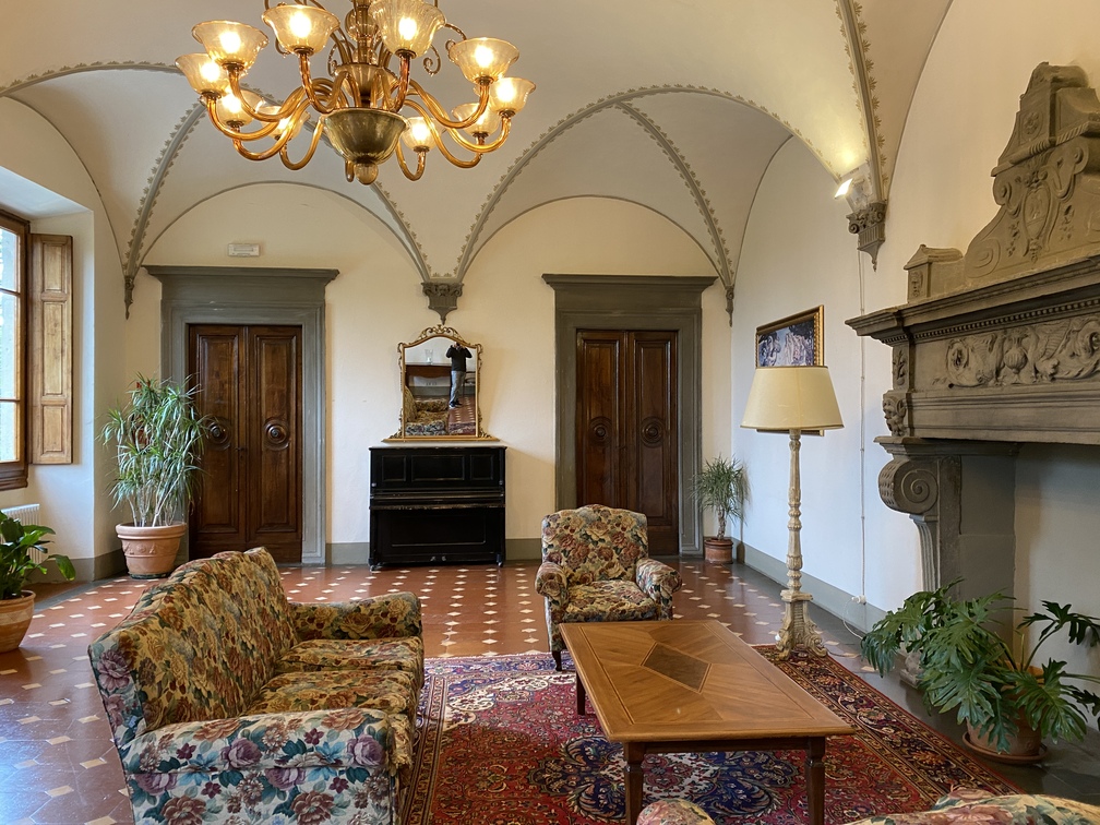 Villa Castelletti - sala rossa con divani, poltrone, camino e piante.