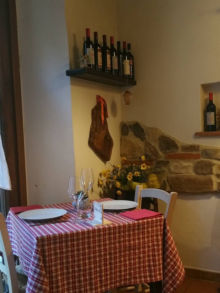 Osteria Le Fate Briache - tavolo apparecchiato con tovaglia a quadri, bottiglie di vino.