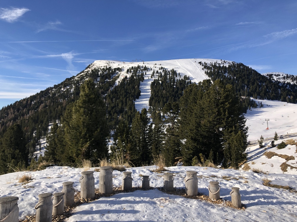 Installazione di bidoni del latte in legno; dietro, Pala Santa.