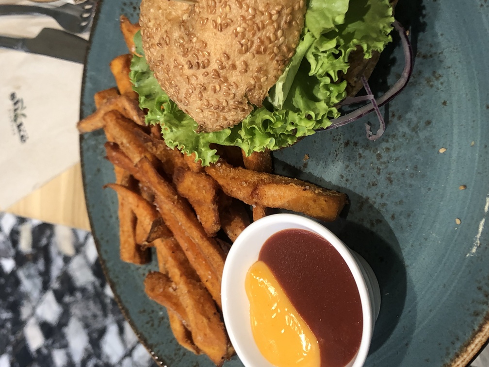 Shake Cafè a Firenze - Hamburger vegano con pane senza glutine, farcitura di avocado, pesto, cipolla, pomodori e lattuga, salsa di capperi e tahini, hamburger di legumi, patate dolci fritte e due salse.