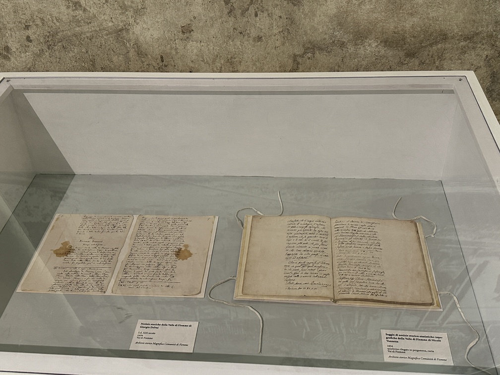 1. "Notizie storiche della Valle di Flemme di Giorgio Delvai", S.d. XIX secolo, carta, Val di Fiemme, Archivio storico Magnifica Comunità di Fiemme. 2. "Saggio di notizie storico-statistiche-topo-grafiche della Valle di Fiemme di Nicolò Vanzetta, 1834, quaderno rilegato in pergamena, carta, Val di Fiemme, Archivio storico Magnifica Comunità di Fiemme.