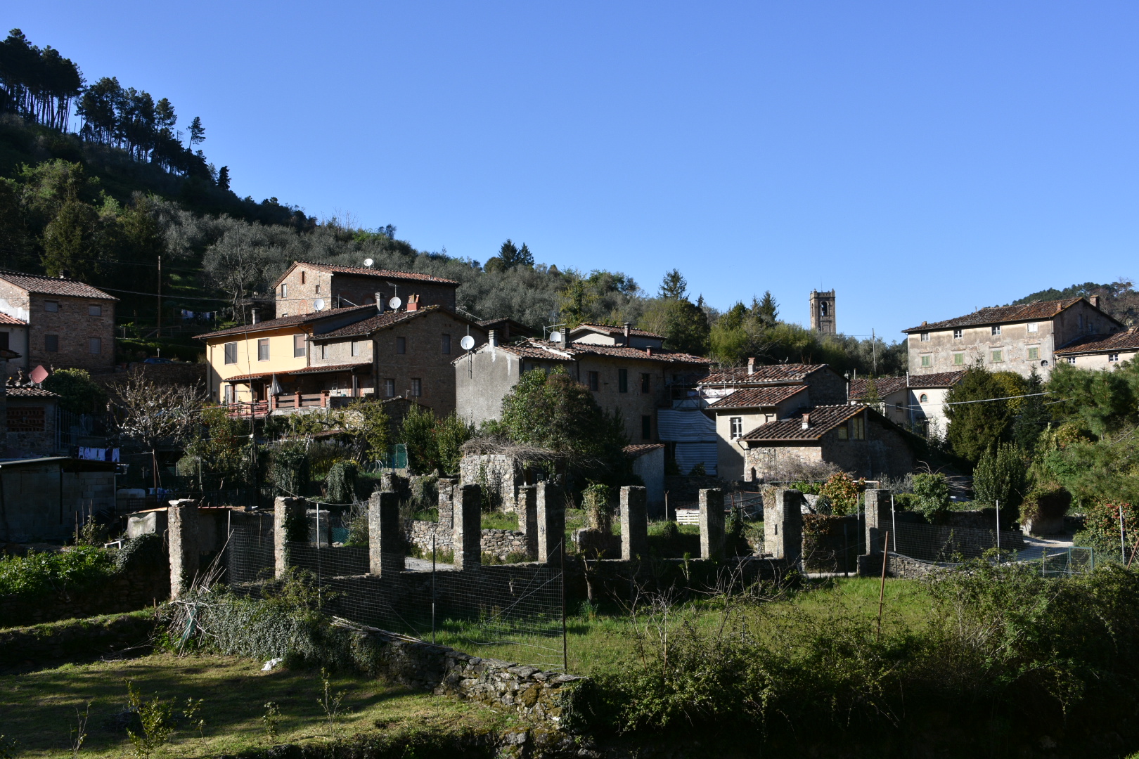 Borgo con case, muri medievali, verde della collina.