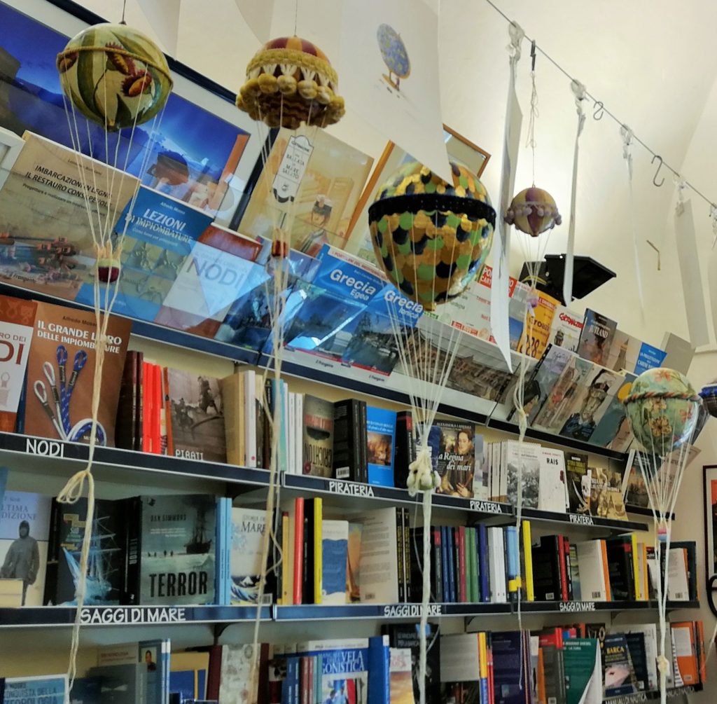 Scaffale di una libreria con appese piccole mongolfiere e disegni.