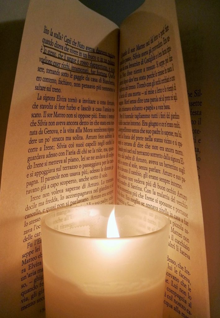 Libro aperto a metà con dentro una candela accesa.