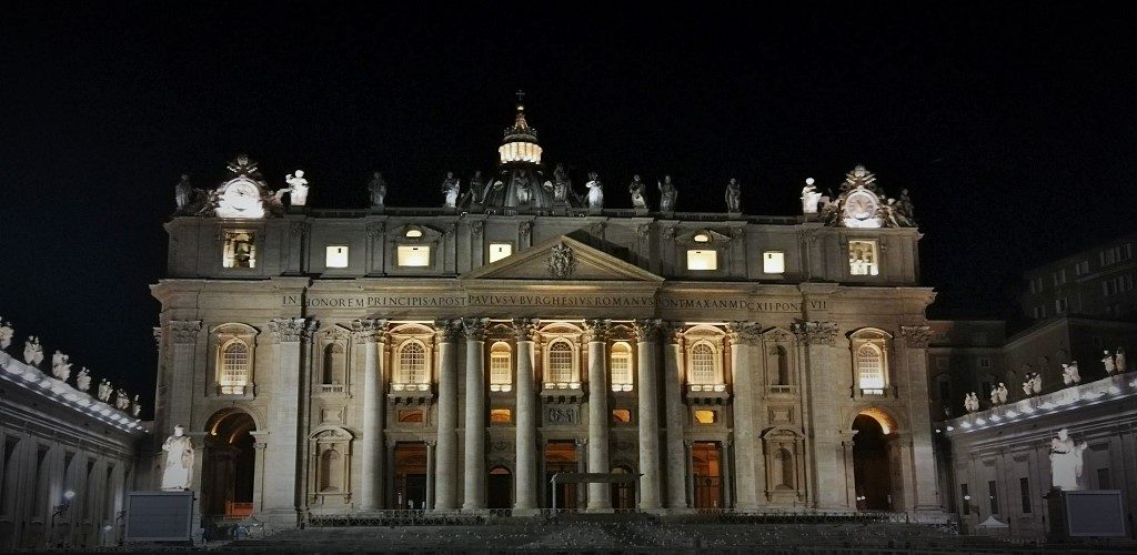Facciata della basilica di San Pietro illuminata di notte.