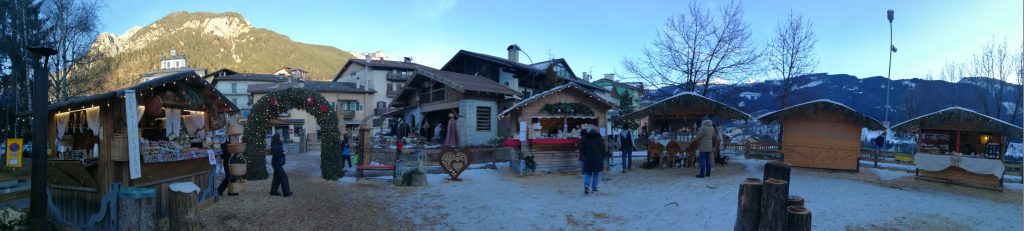 Piazza principale di Tesero, decorata con addobbi natalizi e con le "casine" del mercato di prodotti tipici locali.