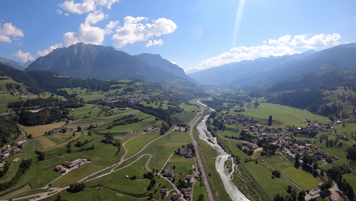 Panorama visto dall'alto della valle con il torrente al centro, paesi e prati, montagne da entrambi i lati.