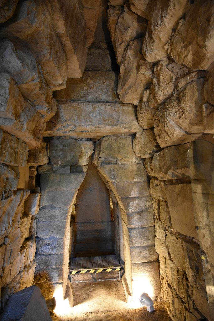 Corridoio di rocce e porta di massi più grandi, oltre un altro ambiente chiuso.