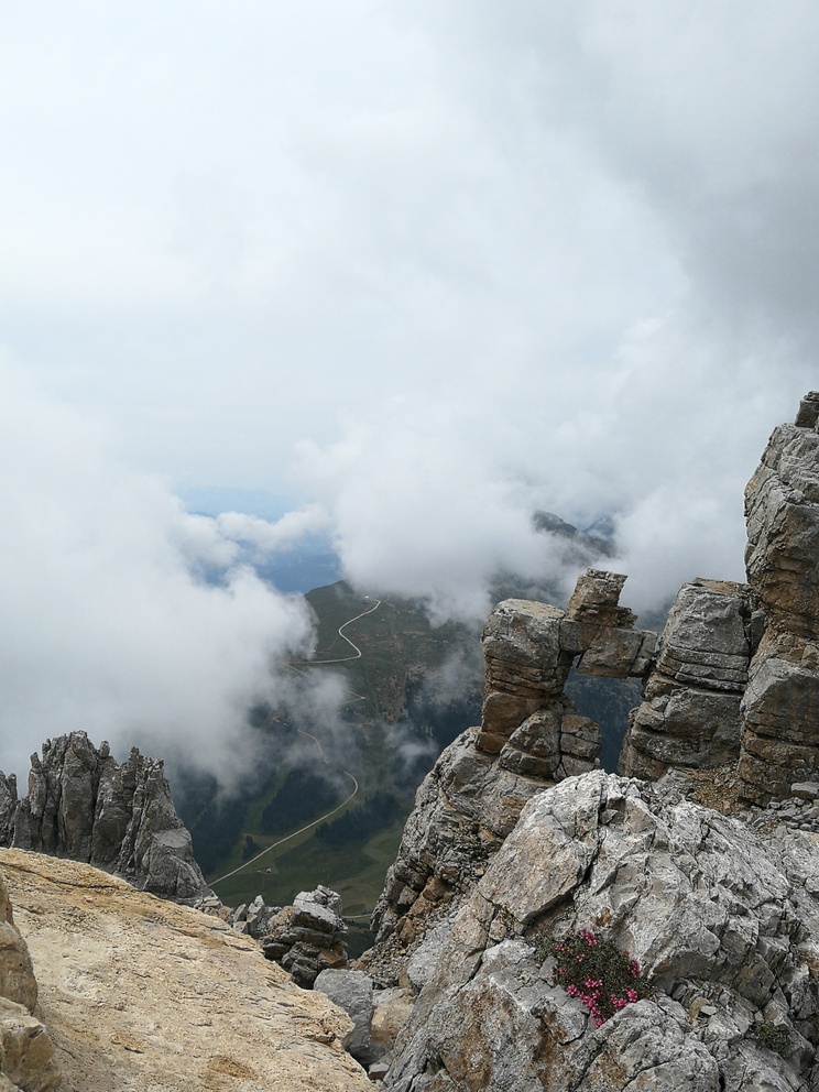 Latemar: catena montuosa, rocce chiare con cielo nuvoloso. Si vede un poco del panorama verdeggiante.