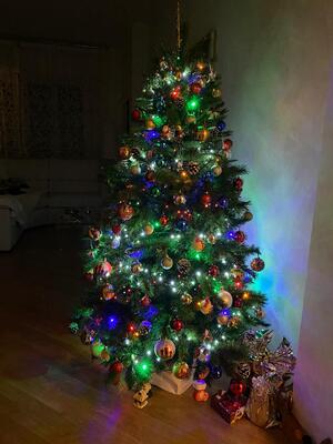 Albero di Natale addobbato con palline e luci colorate, sotto alcuni regali impacchettati.