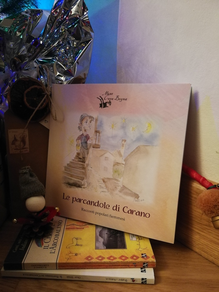 Il libro Le parcandole di Carano sopra Il cervo e l'arcobaleno e Il fantasma di Canterville, a terra, vicino all'albero di Natale.