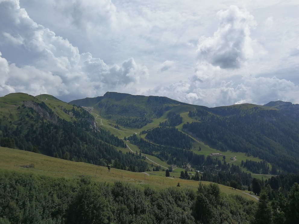 Paesaggio di montagna: boschi, prati e nuvole.
