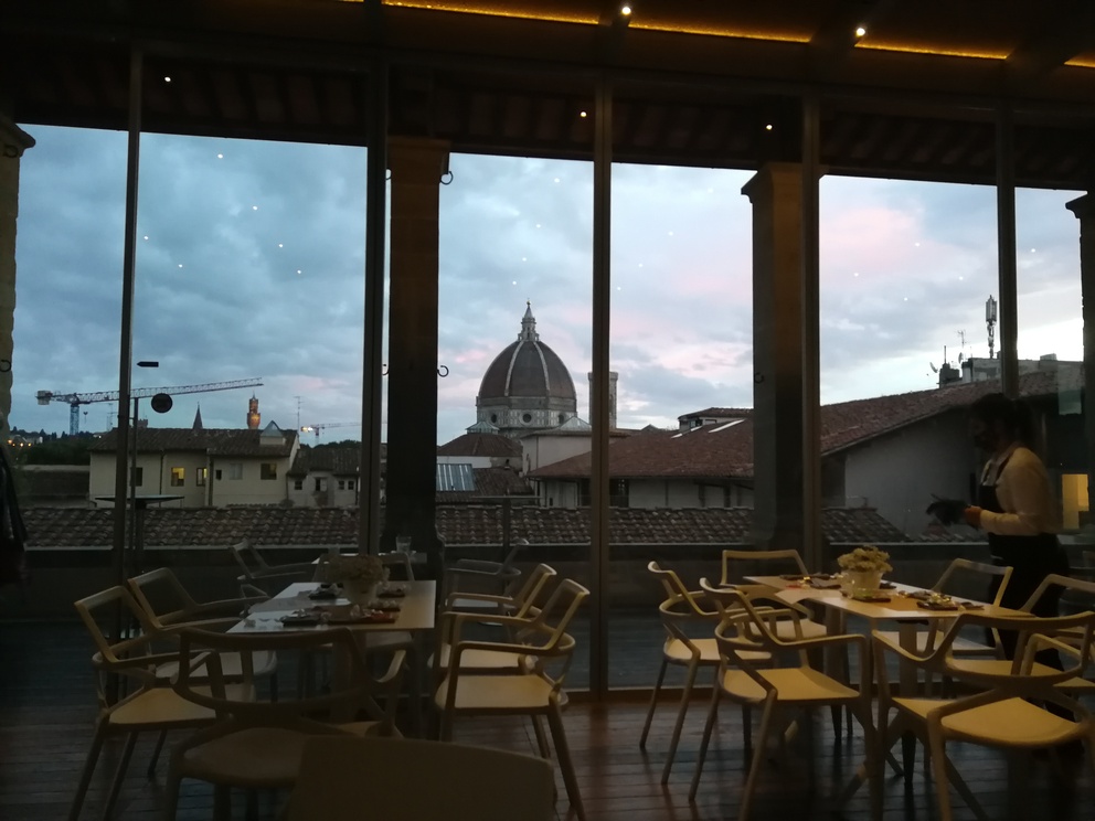 Vista del duomo al tramonto dal Caffè del Verone, dalle vetrate, con tavoli apparecchiati.