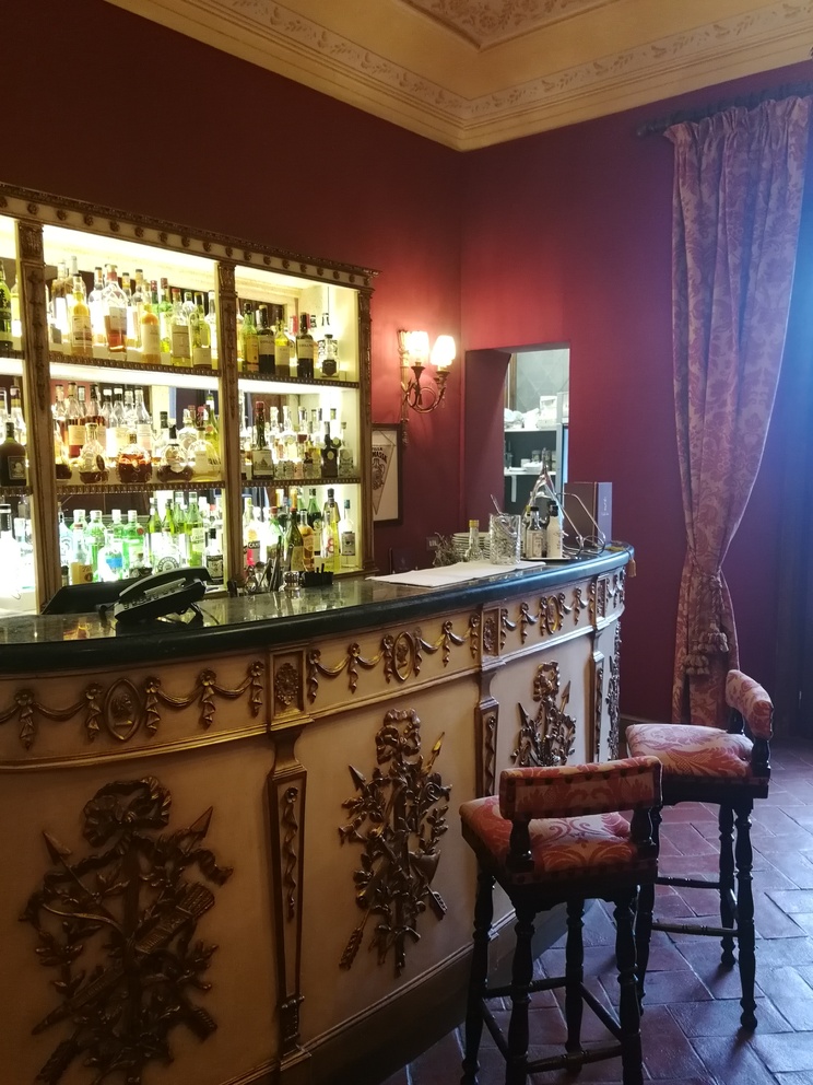 Villa La Massa: bar decorato rosso, sedili e bottiglie di liquori.