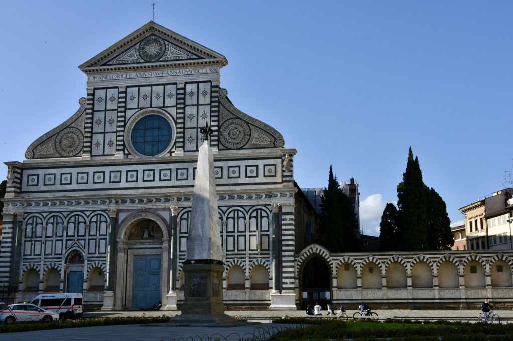 Santa Maria Novella - facciata della chiesa con obelisco nella piazza, alberi e cielo azzurro.