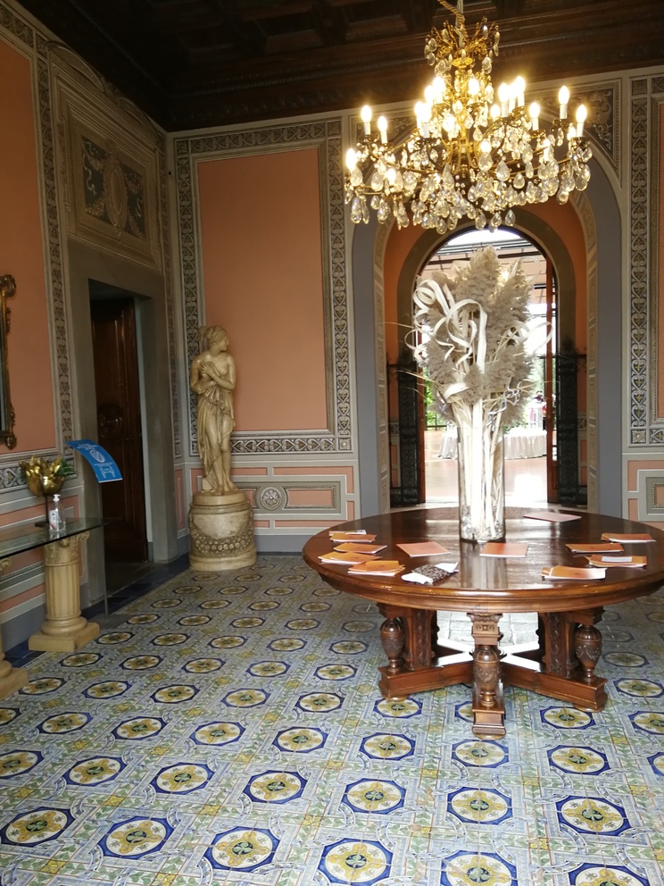 Villa Castelletti - ingresso della villa con tavolo rotondo al centro, statua riproduzione del Canova, lampadario e pavimento colorato.