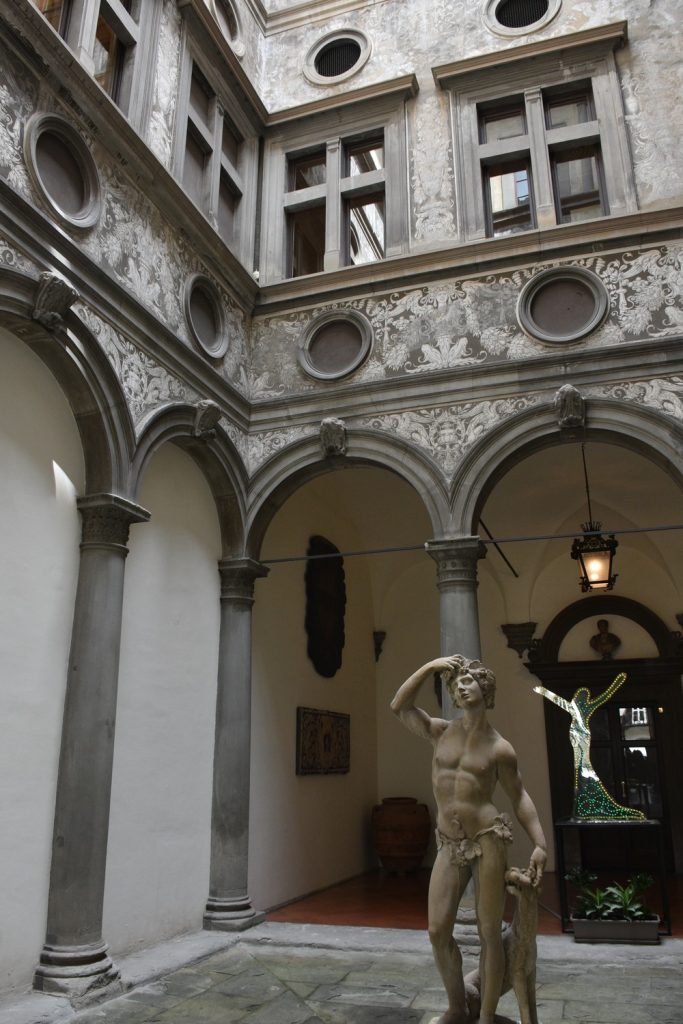 Palazzo Bartolini Salimbeni - cortile con statua, colonne grigie e decorazioni bianche.